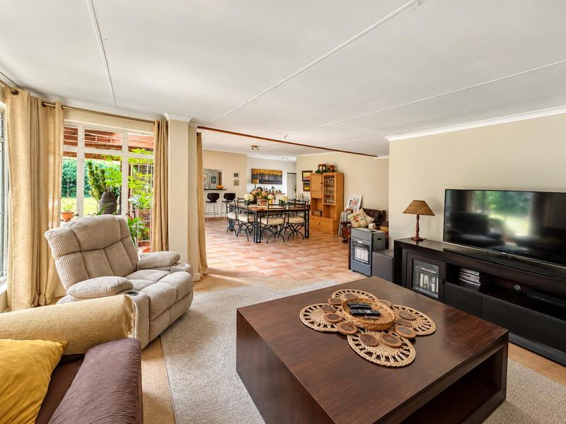 Spacious open-plan living and dining area featuring tiled and carpeted flooring, with seamless flow to an outdoor patio through large sliding glass doors.