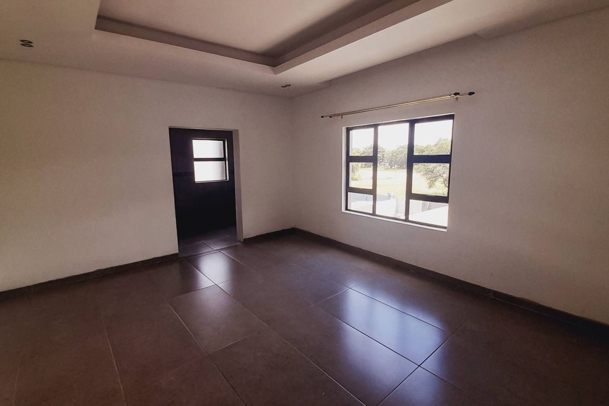 A bright, empty bedroom featuring large windows, tiled flooring, and a modern recessed ceiling design.