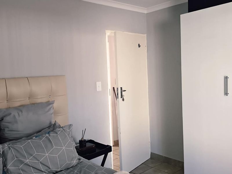 A bedroom featuring tiled flooring, a built-in wardrobe, and neutral wall finishes.