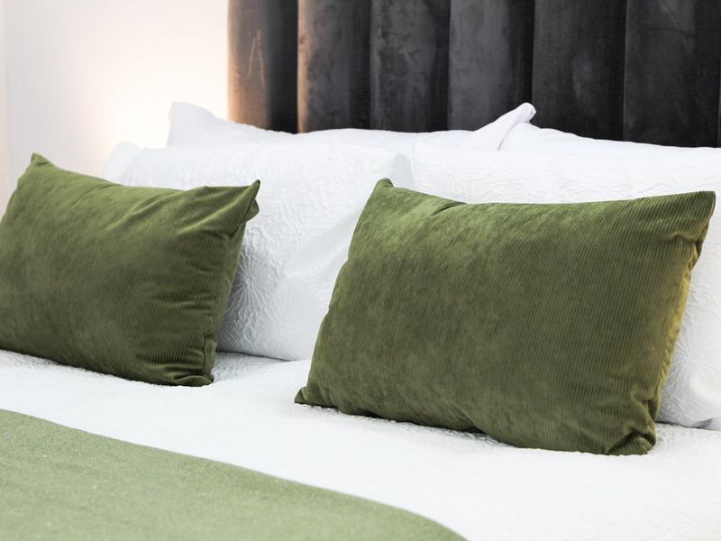 A close-up view of a bedroom featuring a dark, vertical-paneled upholstered headboard.