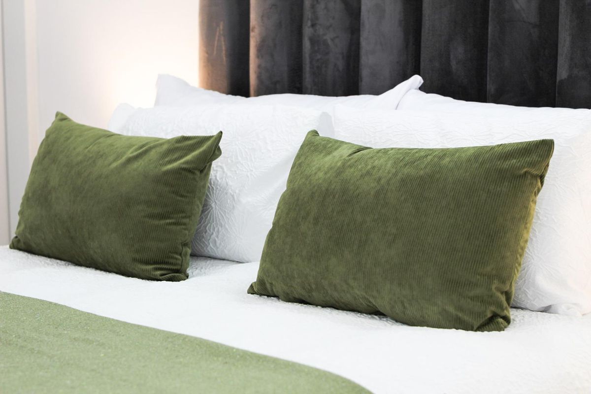 A close-up view of a bedroom featuring a dark, vertical-paneled upholstered headboard.