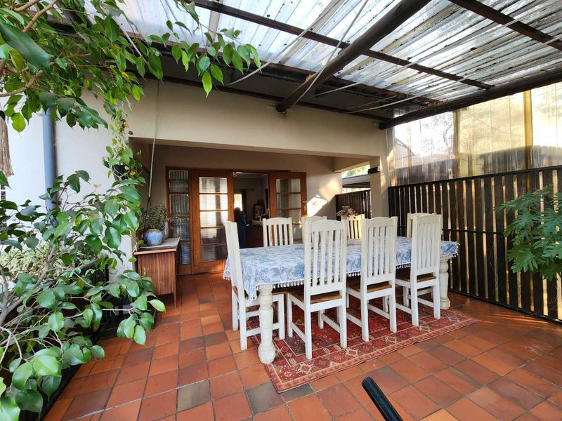 Covered outdoor patio area featuring terracotta tile flooring, timber privacy screening, and a translucent roof structure, providing a sheltered space for outdoor dining.