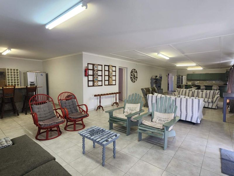 Spacious open-plan living area featuring tiled flooring, integrated kitchen cabinetry, and a breakfast bar, offering a versatile layout for dining and relaxation.