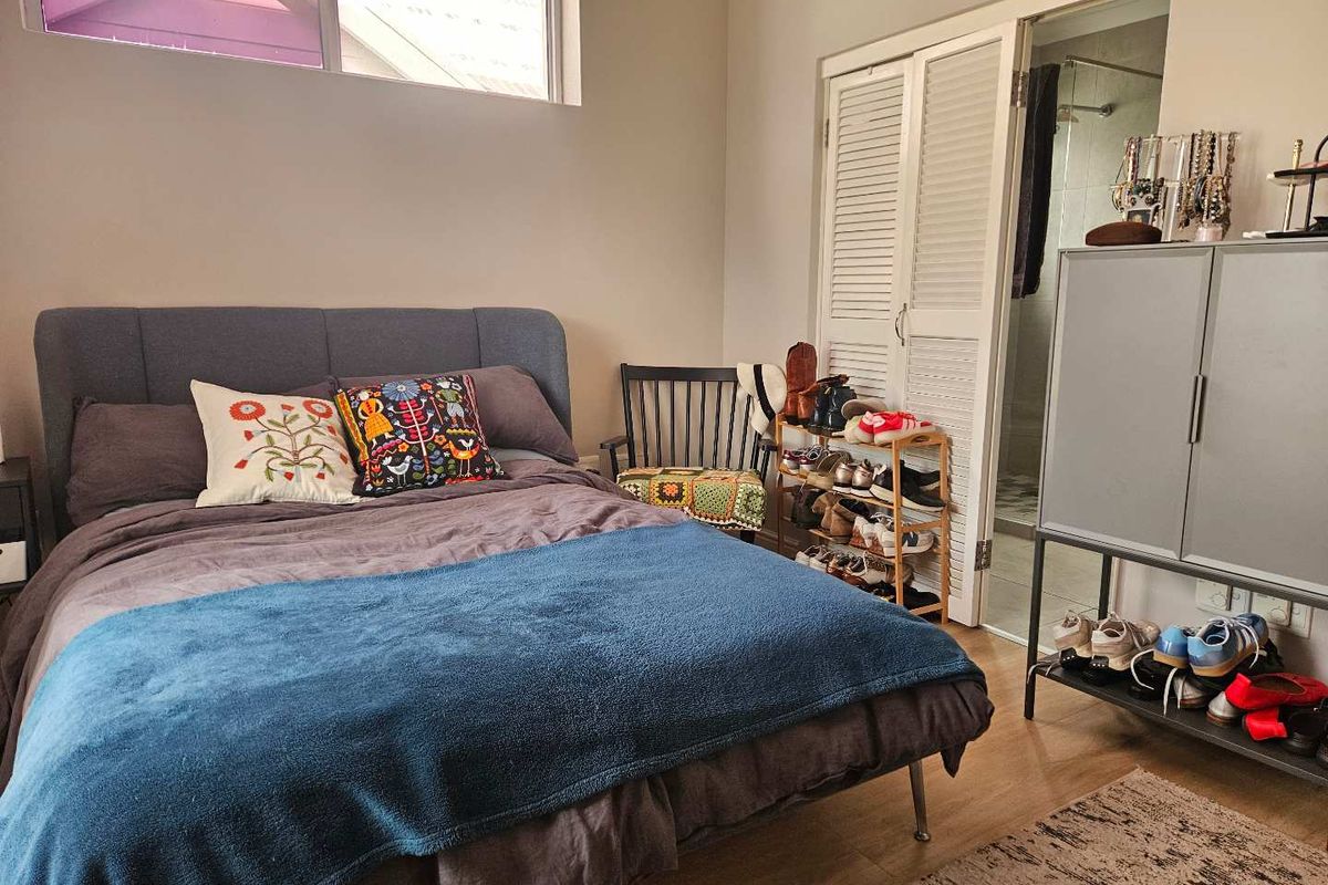 A well-maintained bedroom featuring laminate flooring, louvered closet doors, and direct access to an en-suite bathroom.