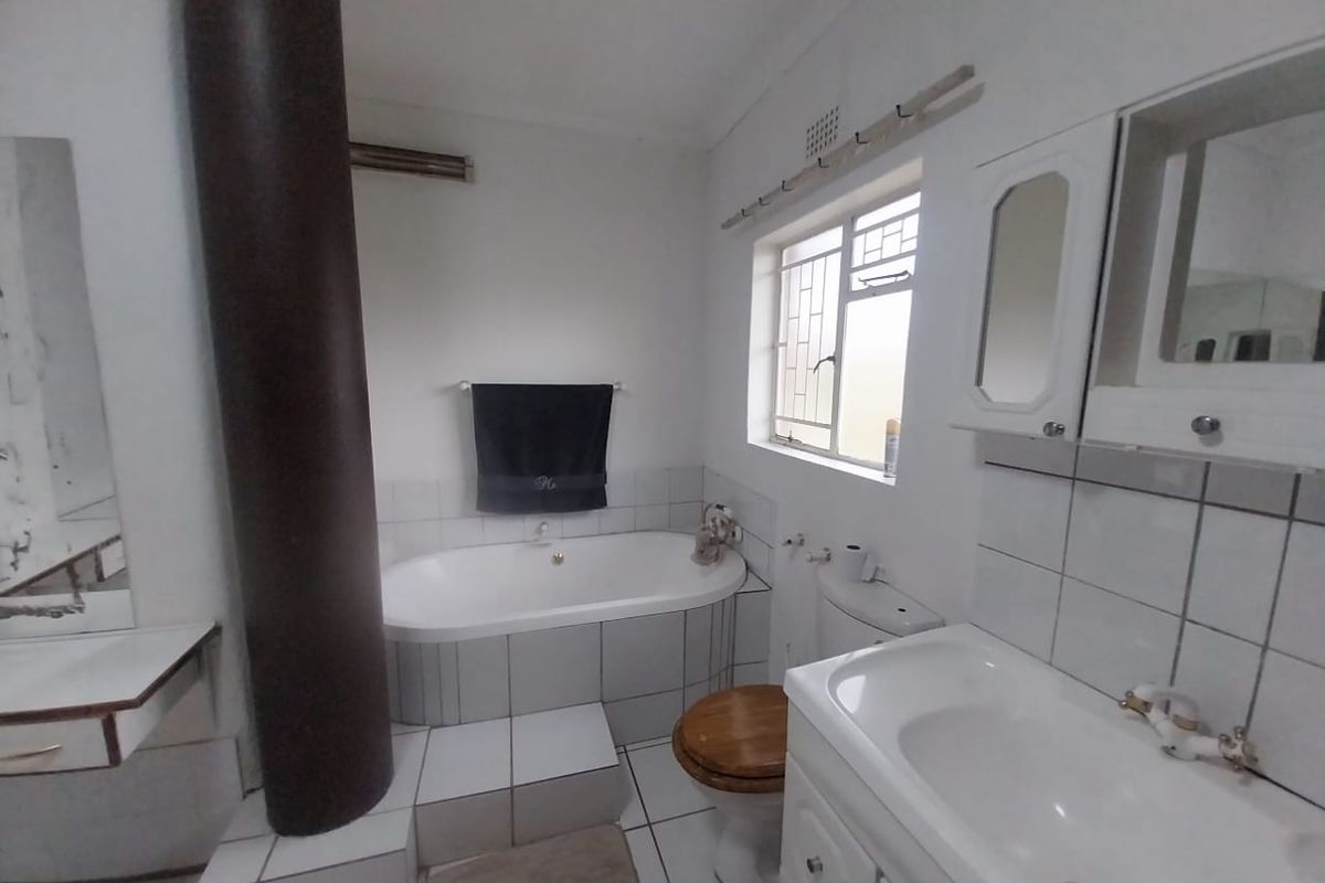 A dated bathroom featuring a built-in bathtub, tiled vanity with storage, and a toilet, requiring cosmetic updates to modernize the space.