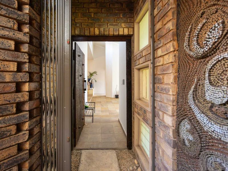 A welcoming entrance featuring textured exposed brickwork, a secure metal gate, and tiled flooring leading into the main living area.