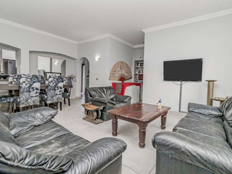 Spacious open-plan living and dining area featuring neutral tiled flooring, coved cornicing, and a functional archway connecting to the kitchen space.