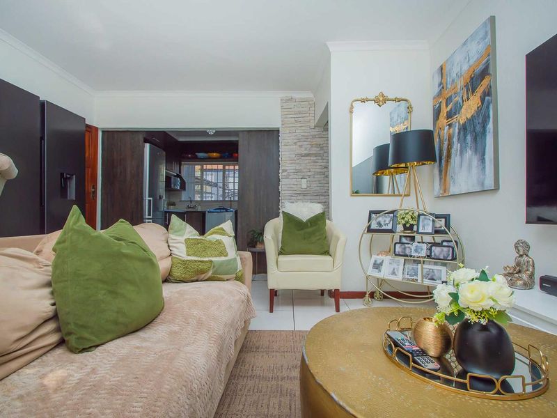 Open plan living area featuring a stacked stone accent wall, neutral tiled flooring, and a seamless transition into the adjacent kitchen space.