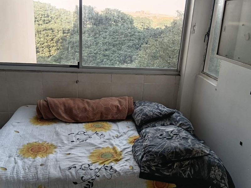 A bedroom featuring a large sliding window with views of surrounding trees and a tiled wall section.