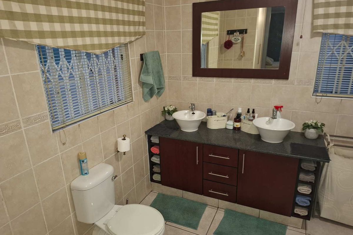 A functional bathroom featuring a double vanity with vessel sinks, tiled walls and flooring, and built-in cabinetry.