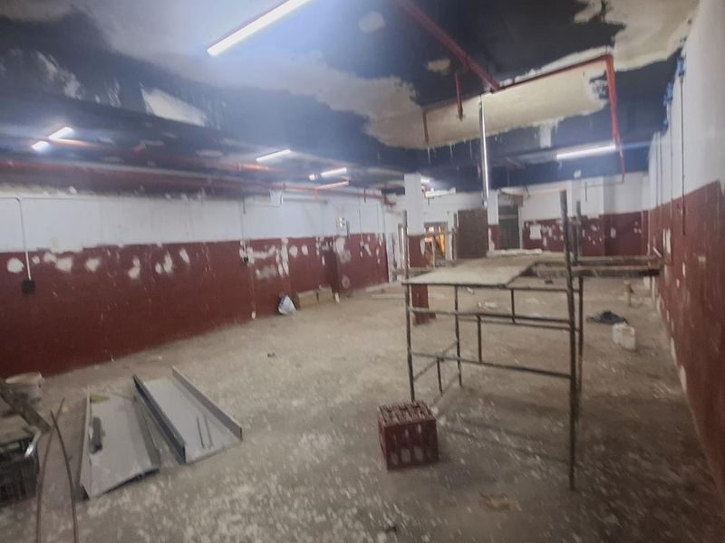 An industrial utility space currently undergoing renovation, featuring exposed ceilings, fire sprinkler systems, and unfinished wall and floor surfaces.