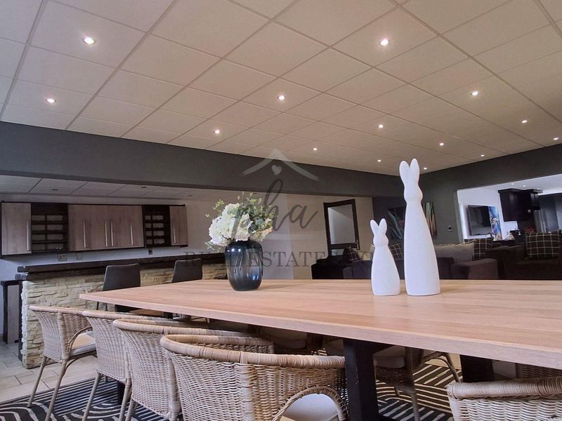 Spacious open-plan living area featuring a built-in bar with stone cladding, recessed downlighting, and a suspended ceiling design.