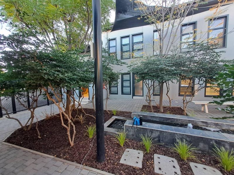 A well-maintained rear courtyard featuring a modern water feature, paved flooring, and established landscaping, providing a pleasant outdoor space for the office building.