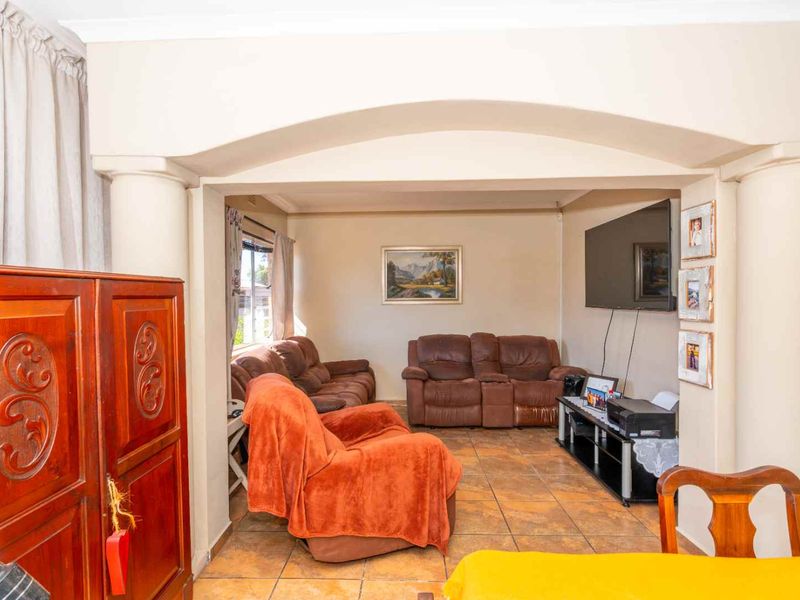 A comfortable living room featuring tiled flooring and a distinct arched architectural opening supported by decorative columns, creating a defined lounge space.