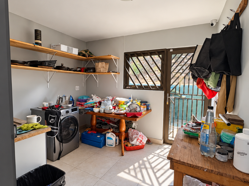 A functional laundry room featuring tiled flooring, built-in wall shelving, and direct access to an outdoor area through a security gate.
