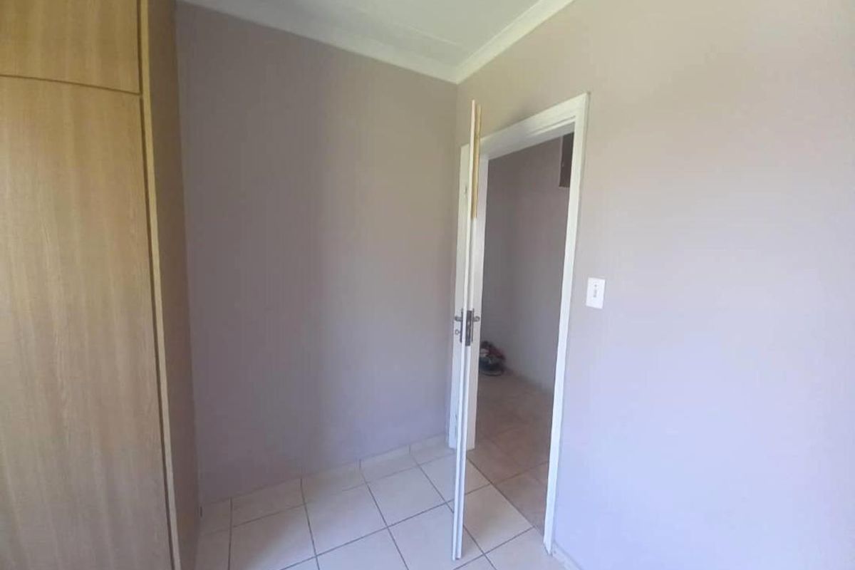 A bedroom interior featuring built-in wooden cabinetry, tiled flooring, and a doorway leading to an adjacent space.
