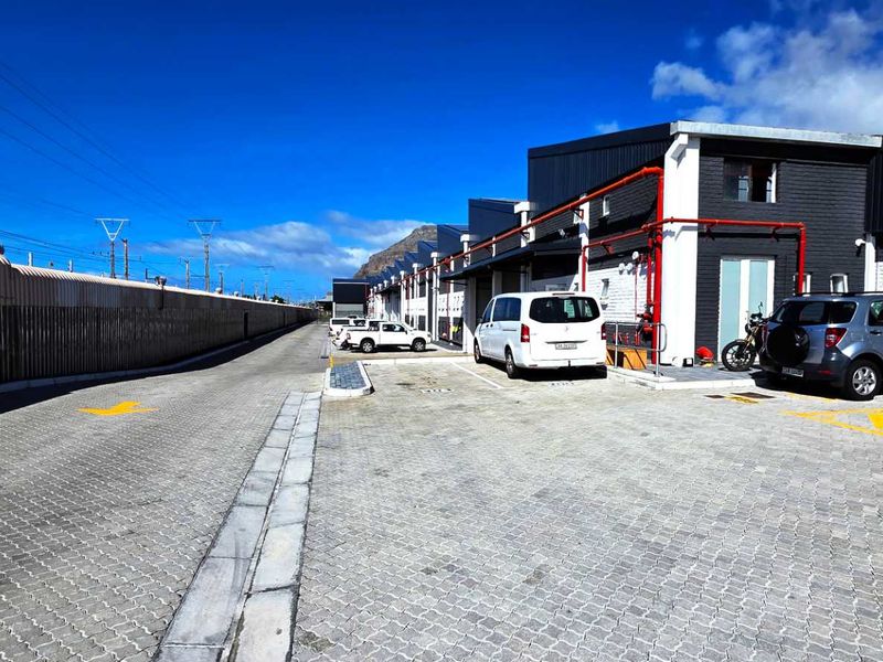Exterior view of an industrial property complex featuring paved parking bays, modern metal cladding, and visible fire safety infrastructure.