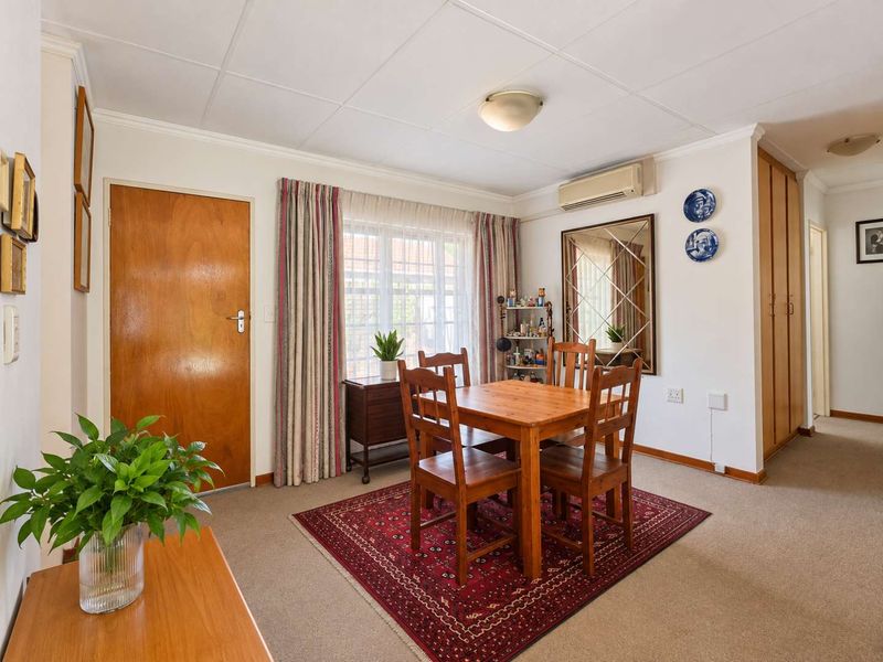 A well-lit dining area featuring carpeted flooring, a split-system air conditioner, and built-in storage cupboards, offering a functional space for meals.