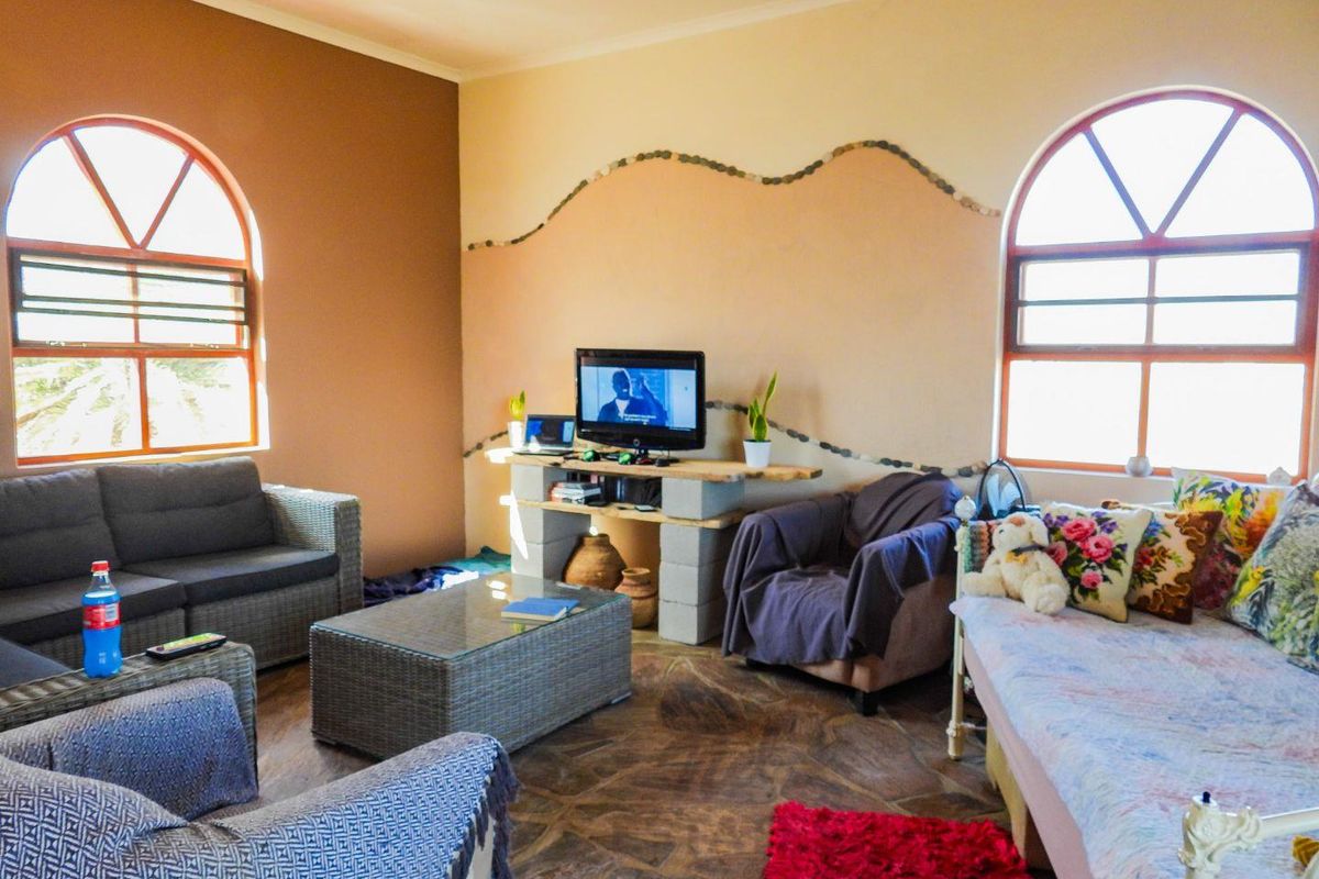 A living room featuring arched windows, tiled flooring, and a unique stone-accented wall design, providing a rustic aesthetic.