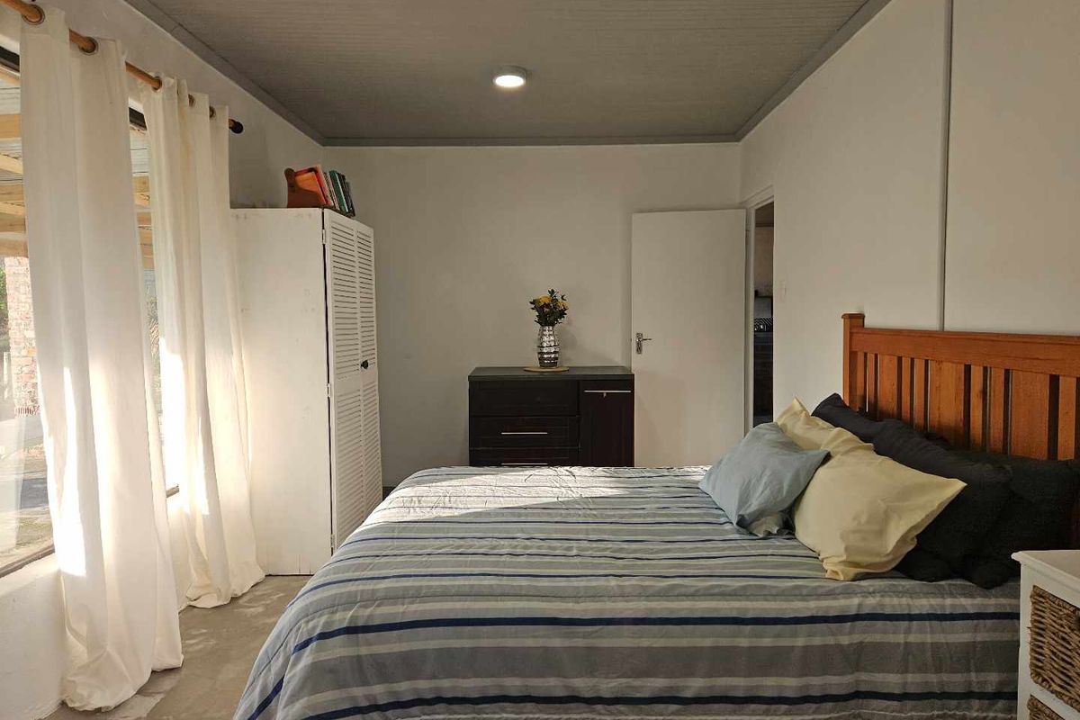 A bedroom featuring a painted timber ceiling with recessed lighting, large windows, and a concrete floor finish.