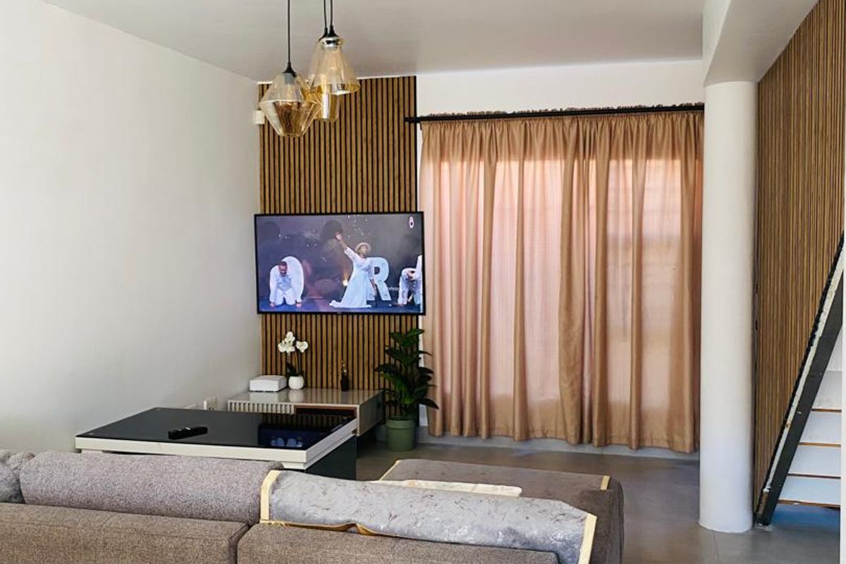 Modern living room featuring contemporary slatted timber wall paneling, neutral tiled flooring, and stylish pendant lighting, creating a warm and inviting atmosphere.