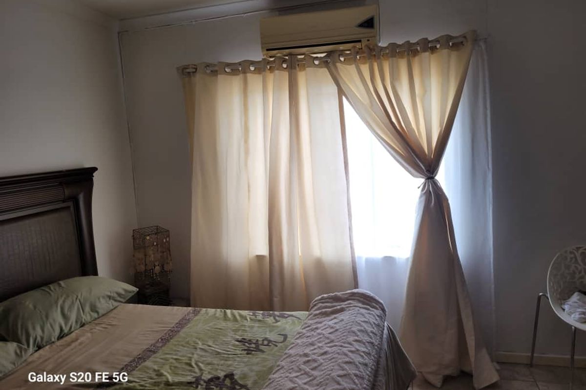 A bedroom featuring tiled flooring and a wall-mounted air conditioning unit.