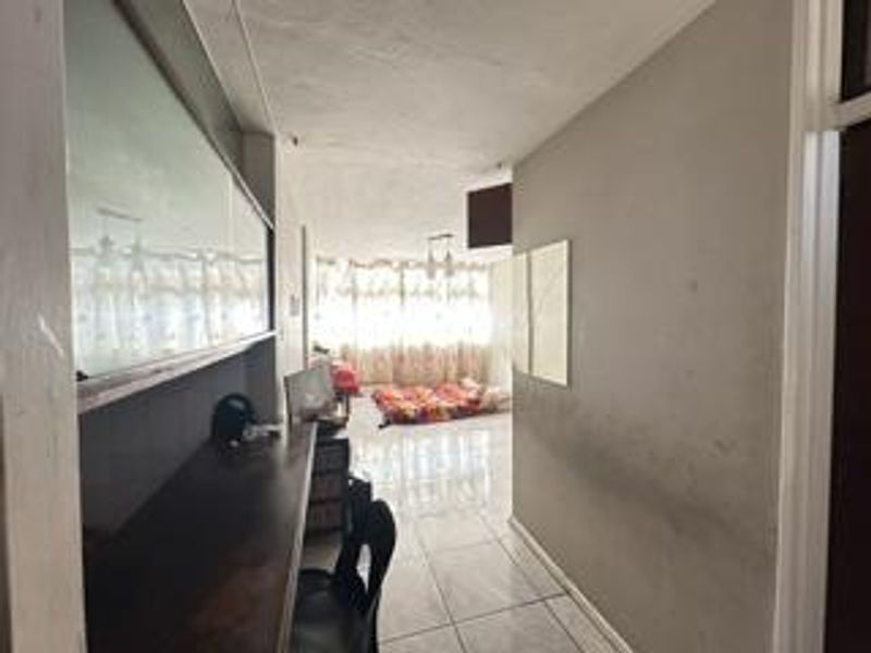 A living area featuring tiled flooring and a built-in desk, showing signs of wear on the walls.