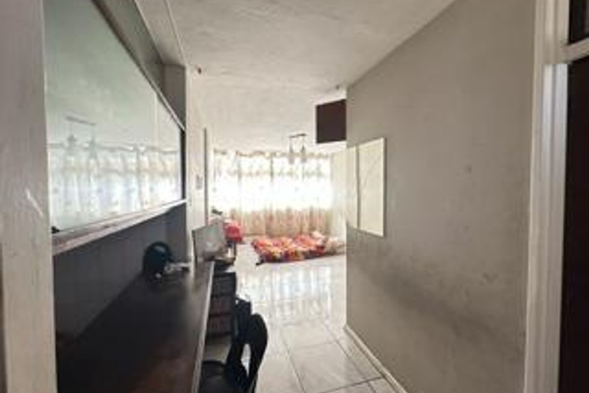 A living area featuring tiled flooring and a built-in desk, showing signs of wear on the walls.