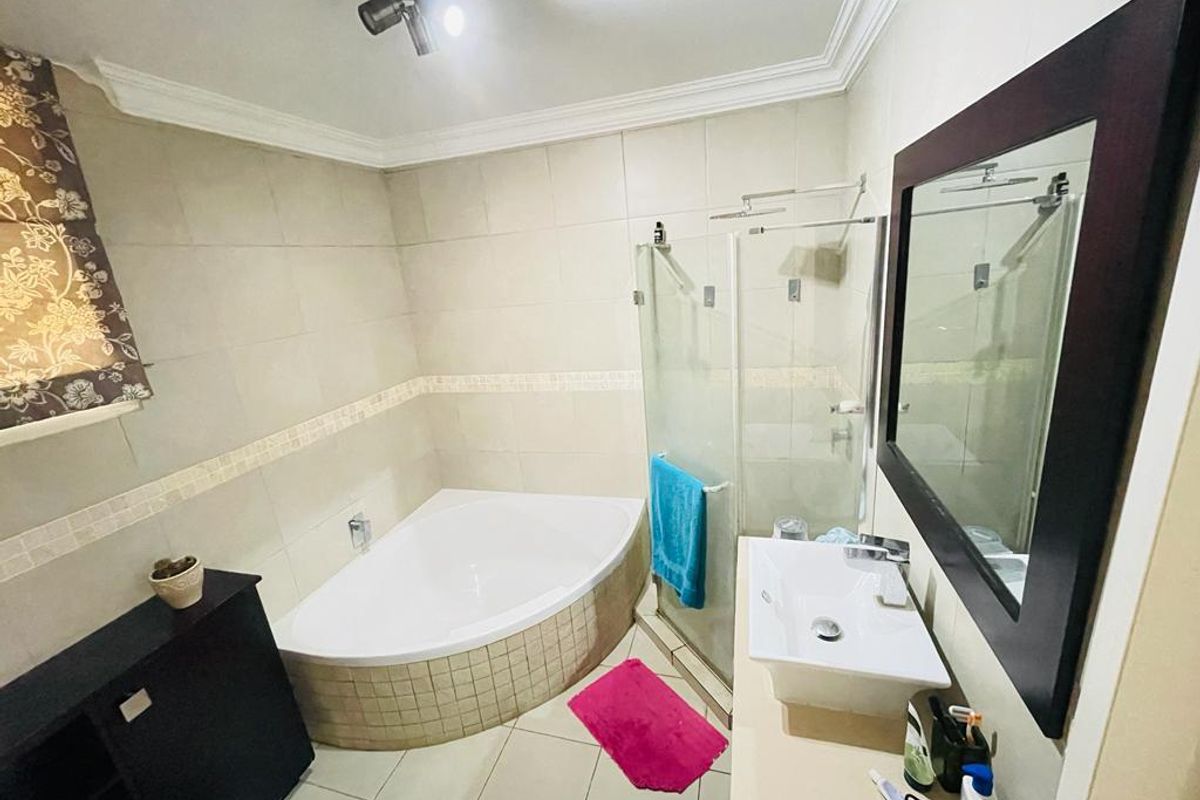 A well-appointed bathroom featuring a corner bathtub, a separate glass-enclosed shower, and a modern vessel sink vanity with tiled finishes.