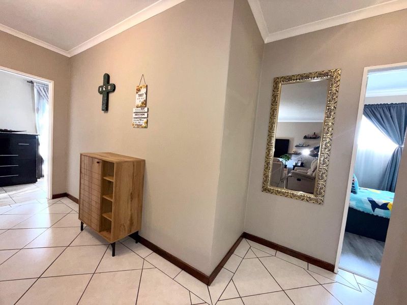 A well-maintained hallway featuring neutral wall tones, tiled flooring, and coved cornicing, providing access to adjacent rooms.
