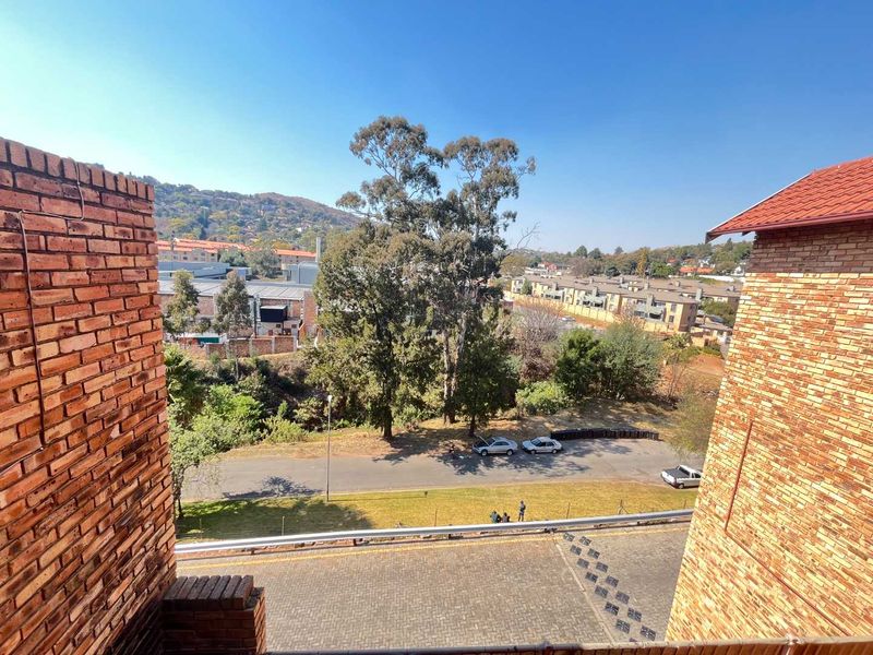 Elevated view overlooking the surrounding neighbourhood, street, and landscaped grounds from the apartment balcony.