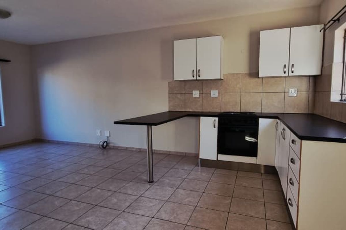 Open-plan living and kitchen area featuring tiled flooring, built-in cabinetry, and a breakfast counter, providing a functional and versatile living space.