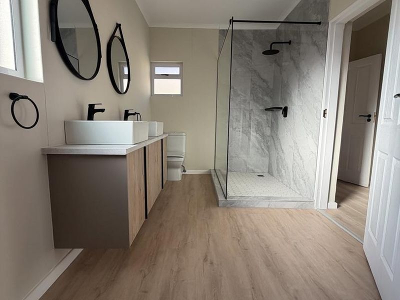 Modern bathroom featuring a double vanity, walk-in shower with glass screen, and contemporary finishes throughout.