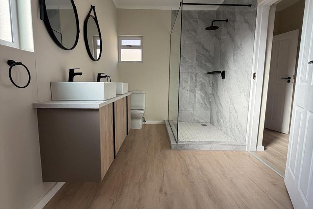 Modern bathroom featuring a double vanity, walk-in shower with glass screen, and contemporary finishes throughout.