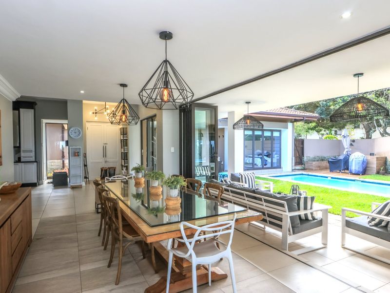 Spacious open-plan living and dining area featuring large stacking doors that open seamlessly to a private swimming pool and garden.