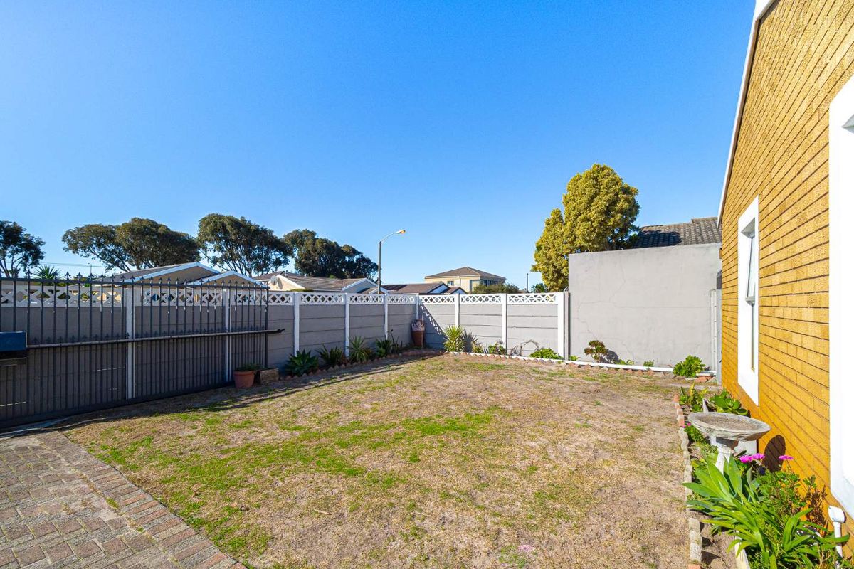 A private rear garden featuring a paved walkway, lawn area, and perimeter boundary walling, providing a secure outdoor space.