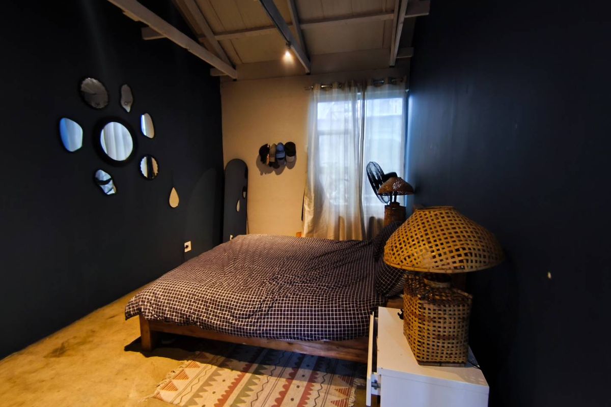 A bedroom featuring exposed timber ceiling beams and polished concrete flooring, creating a rustic and industrial aesthetic.