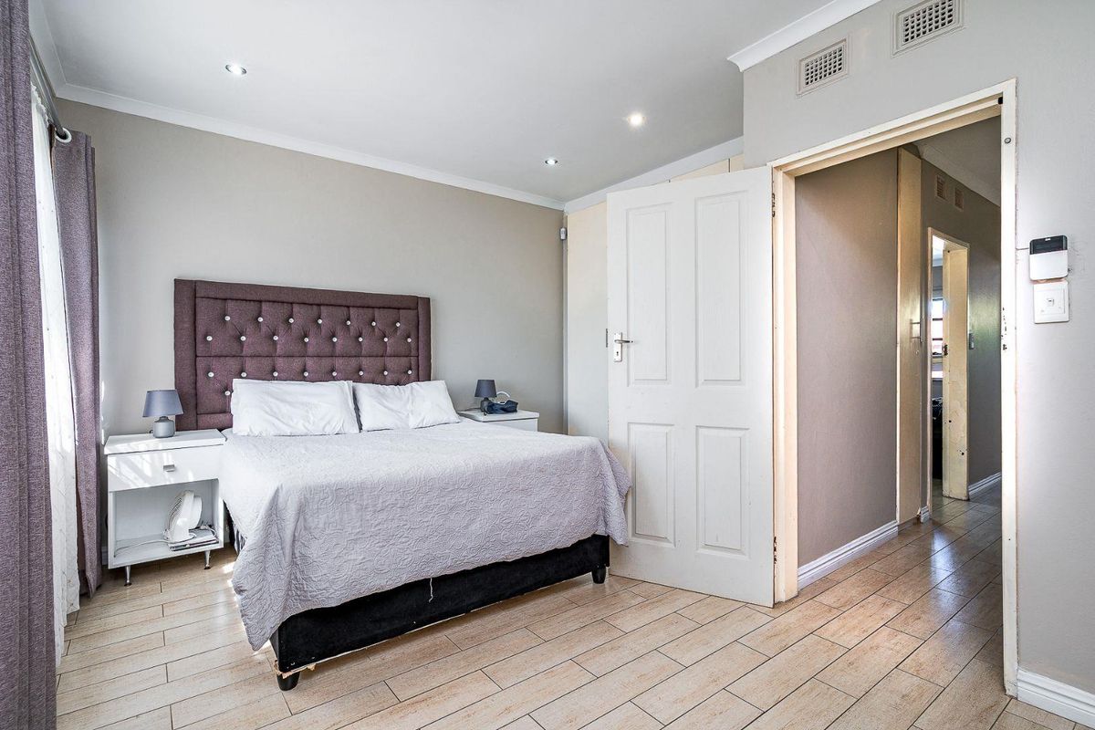 A well-maintained bedroom featuring tiled flooring, recessed downlighting, and built-in cupboards, providing a clean and functional living space.