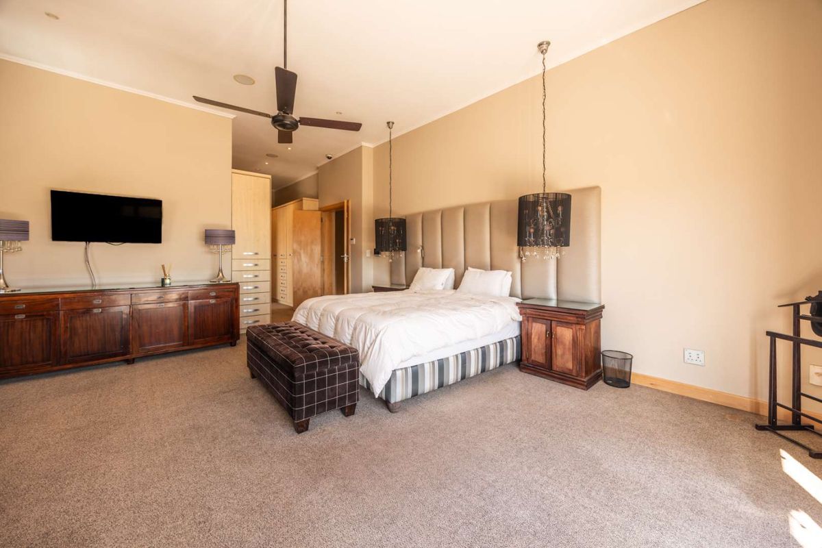 Spacious bedroom featuring a large upholstered headboard, built-in cabinetry, recessed lighting, and a ceiling fan.