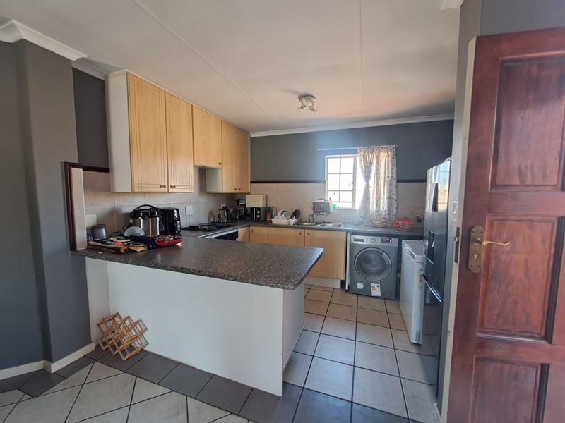 A functional kitchen featuring laminate cabinetry, granite countertops, a breakfast bar, and ceramic tiled flooring with integrated appliance space.