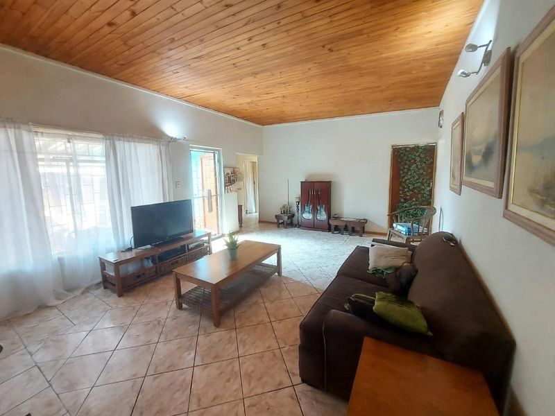 Spacious living room featuring a warm timber tongue and groove ceiling and neutral ceramic floor tiles, offering a comfortable and functional living space.
