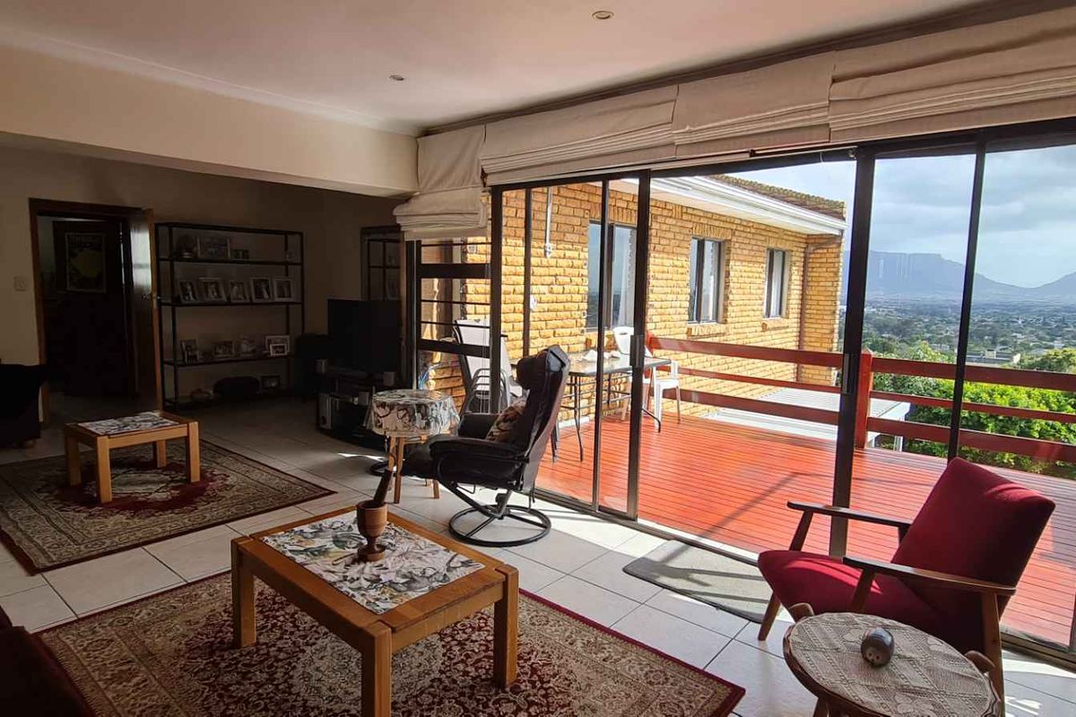 Spacious living area featuring large sliding glass doors that open onto a wooden deck with expansive mountain and landscape views.