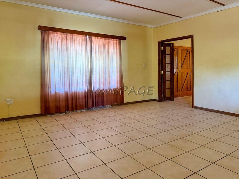 An empty living room featuring tiled flooring and a sliding door, providing a blank canvas for potential interior design updates.