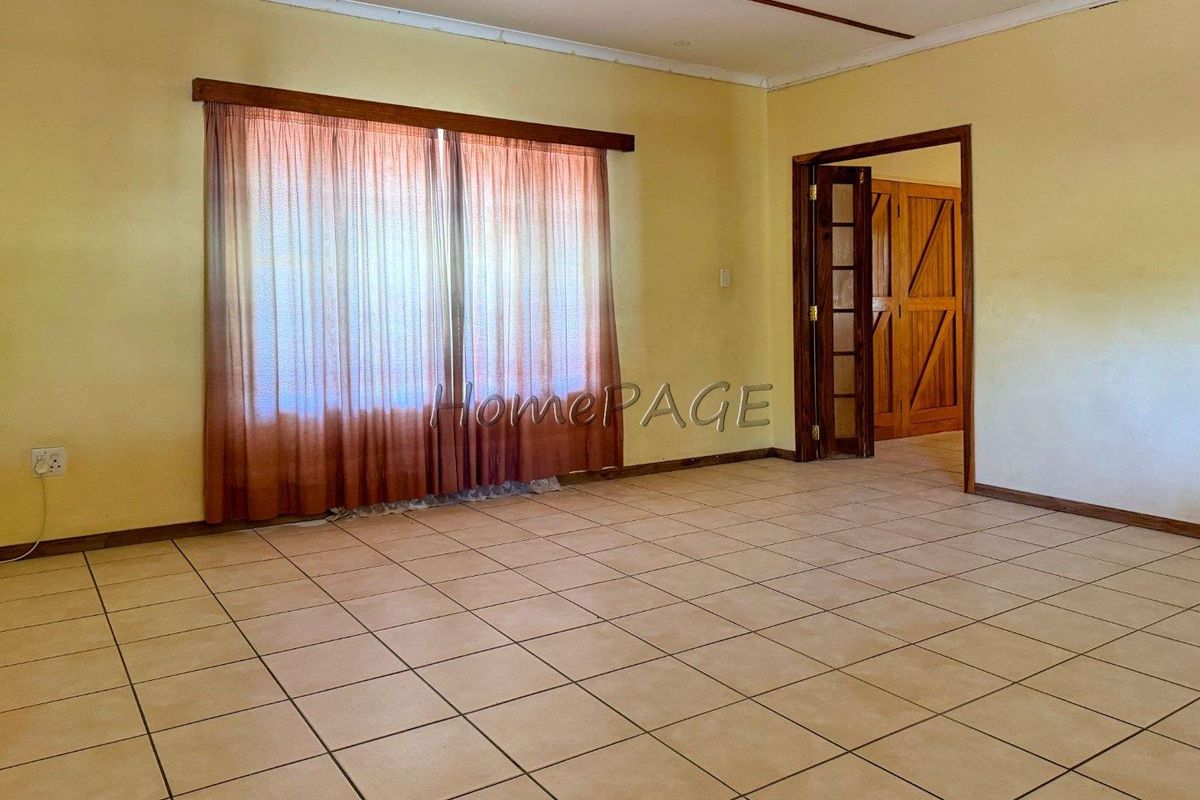 An empty living room featuring tiled flooring and a sliding door, providing a blank canvas for potential interior design updates.