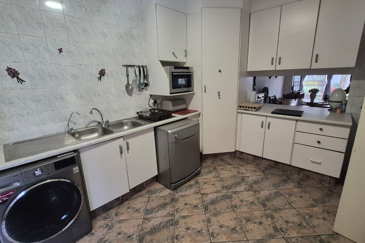 Functional kitchen featuring white cabinetry, laminate countertops, tiled backsplash, and integrated microwave, with tiled flooring throughout.