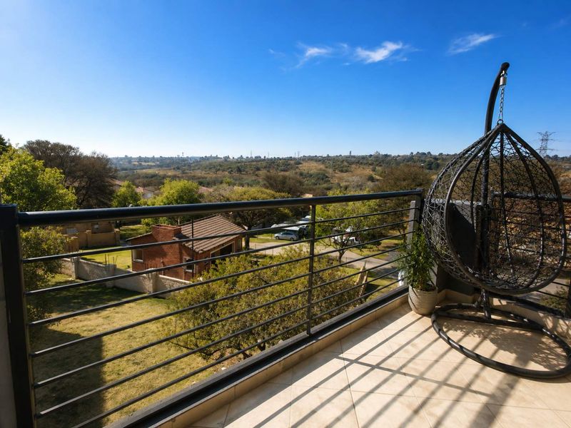 A spacious balcony featuring a metal balustrade and tiled flooring, offering expansive views of the surrounding landscape.
