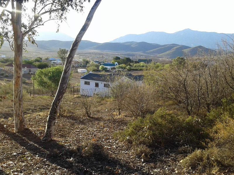 A scenic view overlooking a rural landscape with distant mountains and surrounding natural vegetation.