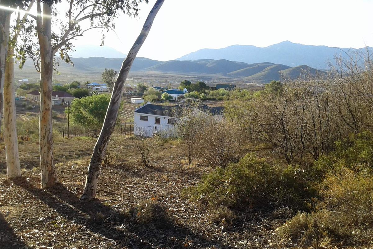 A scenic view overlooking a rural landscape with distant mountains and surrounding natural vegetation.