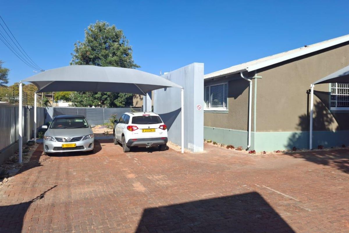 Exterior view of the office property featuring a paved driveway and a covered shade cloth carport for vehicle parking.