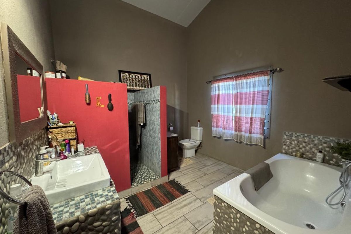 Spacious bathroom featuring a built-in bathtub with stone-cladding, a separate walk-in shower, a vanity basin, and a toilet.